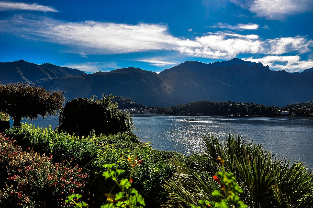 Vista panoramica del Lago di Como in primavera con alberi fioriti e hotel affacciati sul lago.