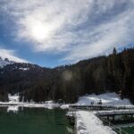 Panorama delle Dolomiti in primavera, con prati fioriti e montagne innevate sullo sfondo.