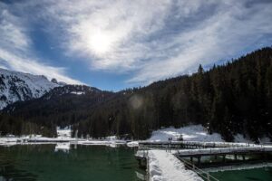 Panorama delle Dolomiti in primavera, con prati fioriti e montagne innevate sullo sfondo.