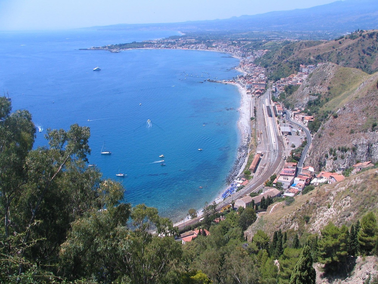 Treno che percorre la costa siciliana, vista panoramica su mare e paesaggi naturali.