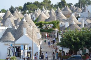 Trulli pugliesi circondati da fiori primaverili e mare cristallino in un itinerario di marzo.