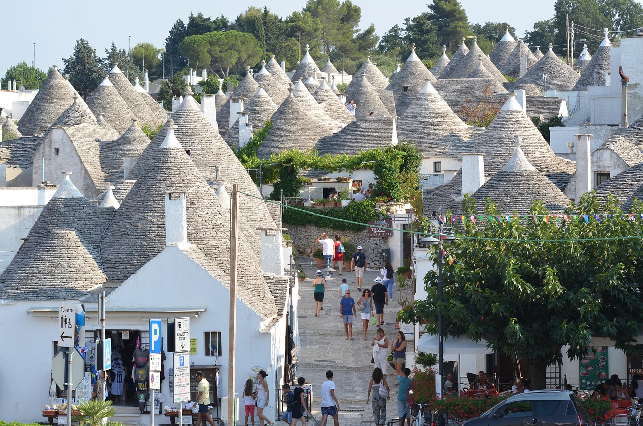 Trulli pugliesi circondati da fiori primaverili e mare cristallino in un itinerario di marzo.